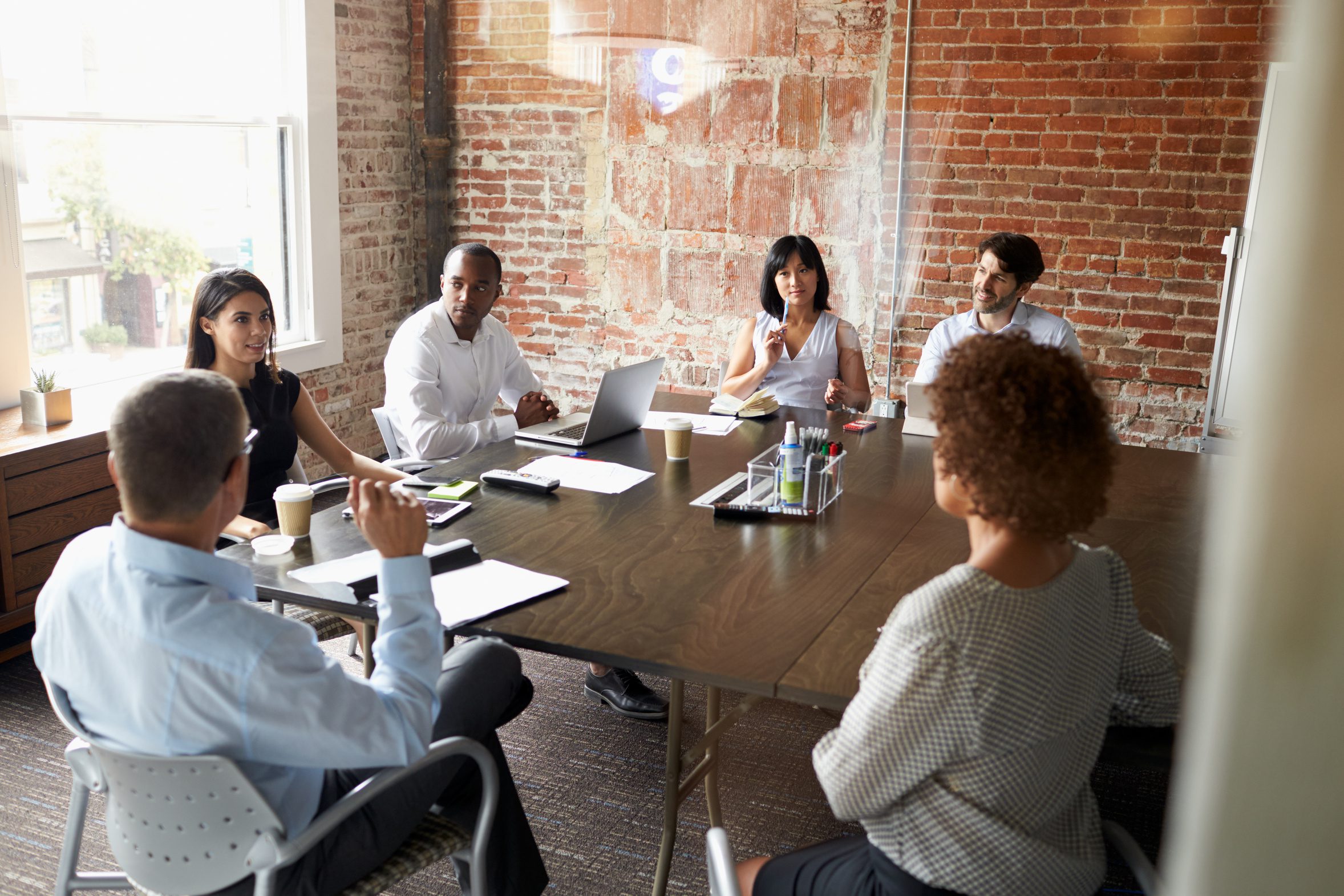 Diverse nonprofit board meeting reviewing governance, giving history and financing documents